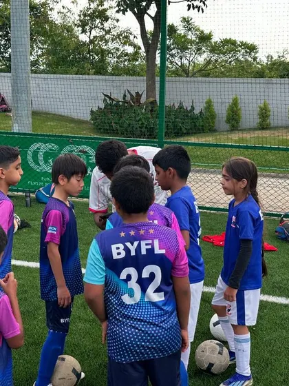 A team huddle in action. The players listen closely to their coach's strategy, a key part of our training that fosters discipline and teamwork from a young age.