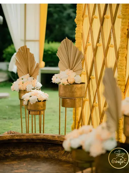 A close-up of the elegant floral arrangements with dried palm leaves, adding a modern touch to the Haldi decor.