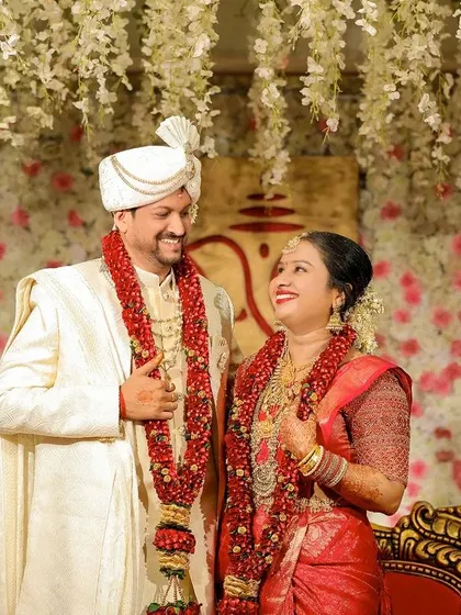 A candid shot of the couple sharing a laugh on stage, with a beautiful floral backdrop creating a romantic atmosphere.
