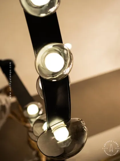 An unconventional design where smoked glass ovals are cradled by a flexible black leather strap. This fixture combines hard and soft textures for a uniquely modern and minimal aesthetic, perfect for creating a talking point in any room.