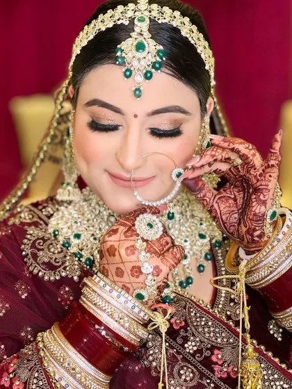 A beautiful pose of the same bride adjusting her nose ring, drawing attention to the intricate jewellery and her perfectly manicured hands.