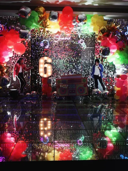 Shimmer and sparkle! A retro disco-themed party with a sequin backdrop, an LED dance floor, and cutouts of Michael Jackson.