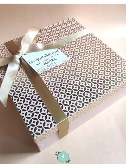 A beautifully wrapped gift box with a "Congratulations" tag, perfect for welcoming a new couple into the family. The elegant geometric-patterned paper and satin ribbon make for a stunning first impression.