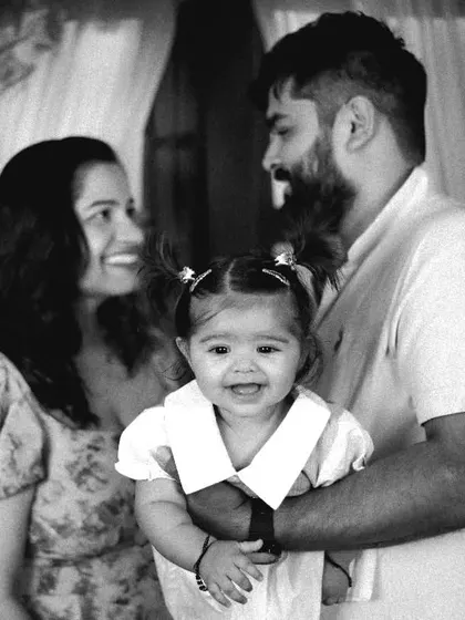 A classic black and white family portrait with the baby girl smiling brightly for the camera.