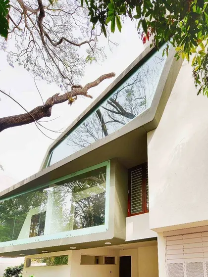 Another perspective of the Mobius Home, highlighting how the angled glass facade reflects the surrounding trees. The design creates a dynamic visual relationship between the building and its natural setting.