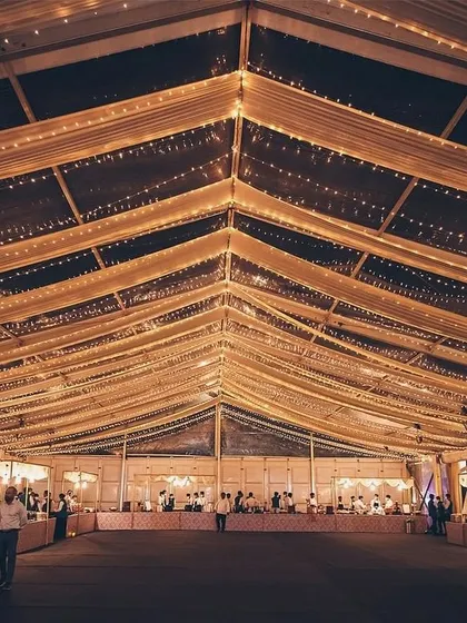 A wide shot of a massive, beautifully lit tent set up for a grand wedding or gala.