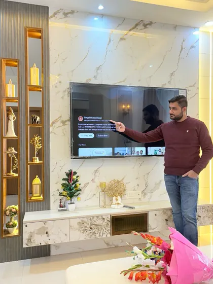 Pointing out the details of our custom TV unit. The combination of materials, including marble-finish laminate, wood, and gold accents, creates a rich and luxurious feel.