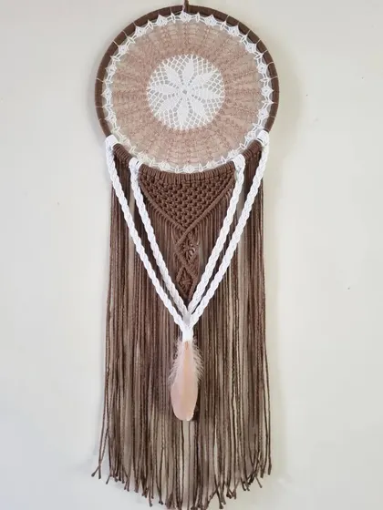 Where rustic meets ethereal. This earth-toned macrame dreamcatcher weaves dreams into reality, capturing the essence of nature's embrace with its brown and white tones.