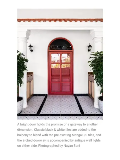 A bright red door promises entry into a new dimension. I used classic black and white tiles on the balcony to blend with the pre-existing Mangaluru tiles, creating a striking and welcoming entrance.