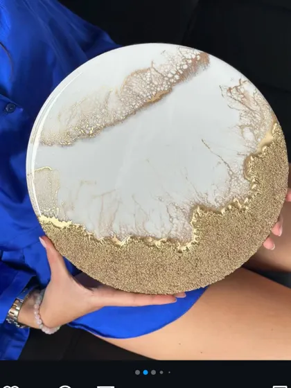 A duplicate of the white and gold resin art, held to show its size and glossy finish.