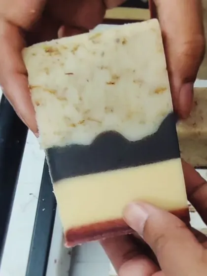 Holding up a bar of the naturally colored soap, showcasing the beautiful, subtle hues.