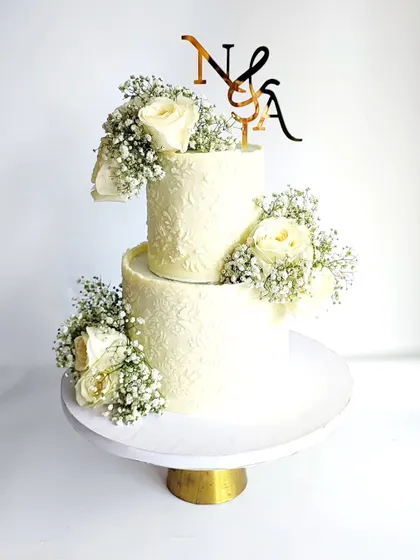 A two-tier white cake with a delicate stencil and fresh flowers. This classic design is perfect for anniversaries, engagements, or even milestone birthdays.