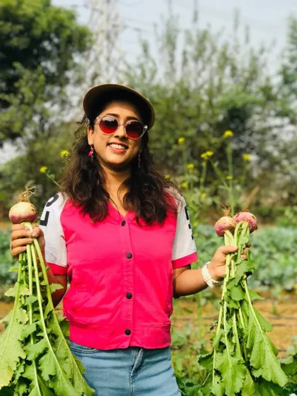 A happy visitor shows off her harvest of fresh turnips. The vibrant colors of the produce are a sign of its freshness and organic quality.