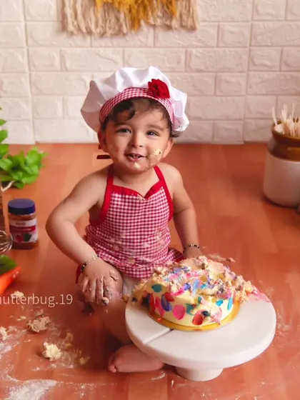 Our little chef is having a blast smashing her very own colorful cake in a kitchen-themed setup.