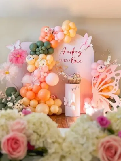 Audrey's butterfly-themed first birthday combined warm peach and olive green balloons with delicate butterfly accents for a sophisticated and whimsical look.