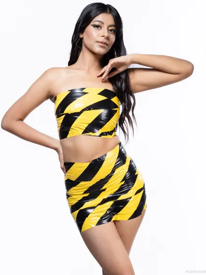 A full-body shot of the caution tape outfit, highlighting the unconventional material and the model's strong pose. This is perfect for a fashion-forward editorial spread.
