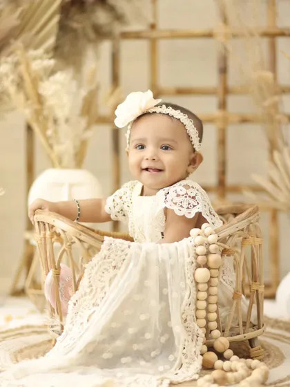 This little girl looks angelic in a white lace dress, seated in a wicker basket. Our boho theme is perfect for creating soft, delicate, and beautiful baby portraits.
