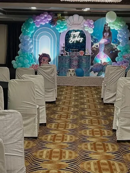 A view of the banquet hall prepared for a mermaid-themed party, with the main stage visible in the background.