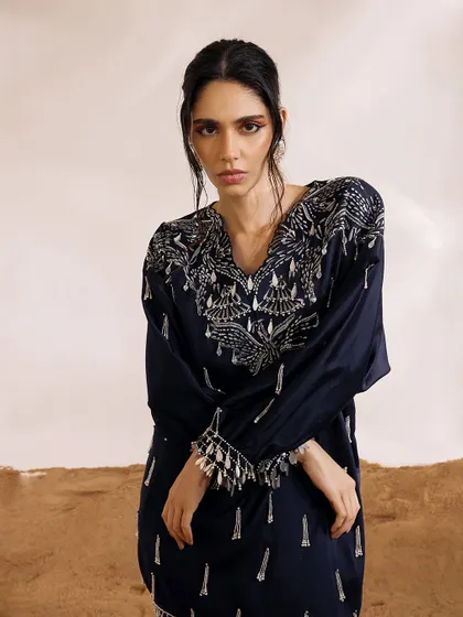 A close-up of the Orion Kaftan's neckline, where phoenix-inspired motifs are brought to life with detailed embroidery and pearl-infused tassels.