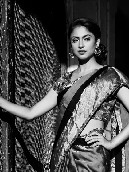 A cinematic black and white shot of a model in a traditional saree. The dramatic play of light and shadow gives this image a timeless, old-world feel.