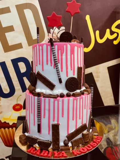 A 4kg two-tiered cake with a pink drip effect, overloaded with KitKats, Oreos, and other chocolate treats.