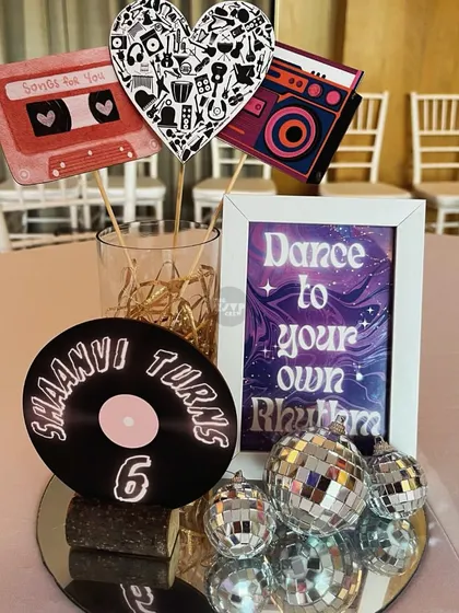 'Dance to your own rhythm'. A retro-themed centerpiece with a mini record, cassette tape cutouts, and disco balls.