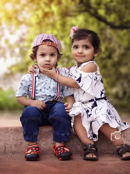 An adorable outdoor portrait of a brother and sister. The gentle interaction as she touches his chin makes for a truly special and authentic sibling photograph.