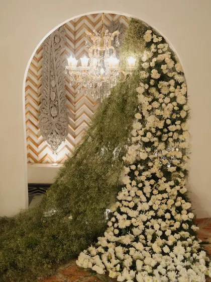A dramatic floral installation featuring a cascade of baby's breath and white chrysanthemums, designed to create a stunning, artistic entrance for a cultural event.