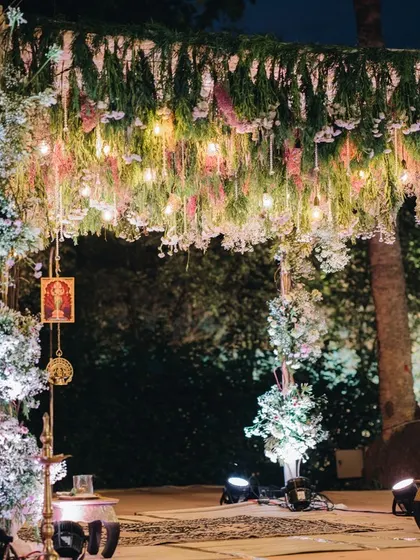 A magical nighttime mandap setup, illuminated by soft lights and adorned with a canopy of flowers, creating an intimate and romantic space for vows.