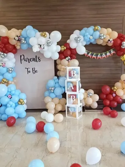 A 'Parents to Be' celebration with a balloon frame in red, blue, and beige, and 'BABY' boxes.