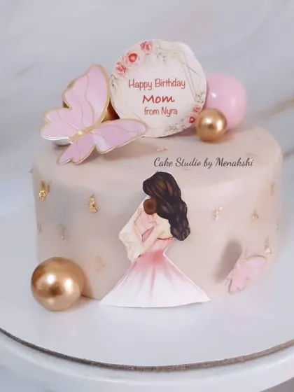 A sweet and delicate birthday cake for a new mom. This no-fondant design features a mother and baby illustration, butterflies, and soft pink and gold accents.