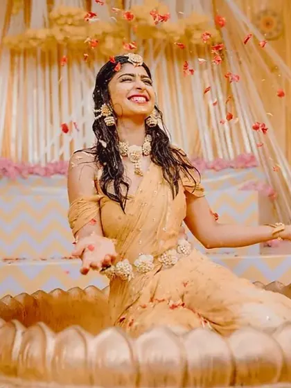 The bride enjoying the flower shower during her Haldi ceremony. It's moments like these that we love to create the perfect setting for.