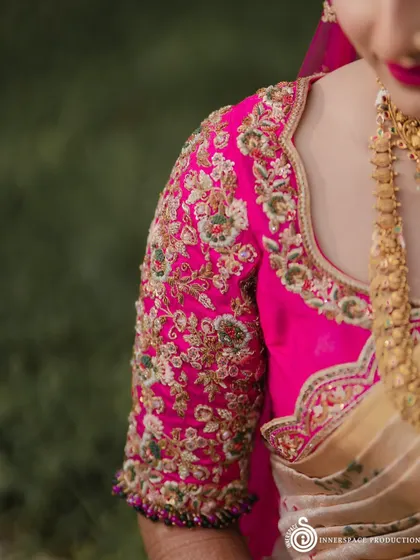 A closer look at the craftsmanship. The sleeve of this bride's pink blouse features dense floral embroidery, a testament to the hours of handwork that go into creating each bespoke piece.