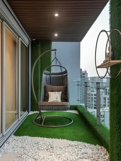 A simple yet cozy balcony with an artificial grass floor and a comfortable swing chair, perfect for relaxing.