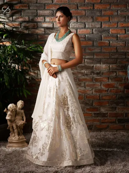 In search of the perfect festive outfit? This white lehenga with gold brocade work, paired with a sleeveless top, is perfect for celebrating new beginnings with grace.