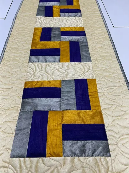 A detail shot of the silk table runner, highlighting the sheen of the fabric and the floral quilting.
