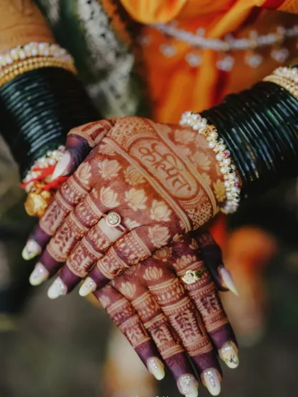 The beautiful dark stain on this Maharashtrian bridal mehendi highlights the groom's name 'Kunal' written in a traditional font on the palm.