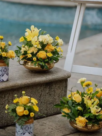 A collection of beautiful floral arrangements in brass and ceramic vases, perfect for a poolside event.