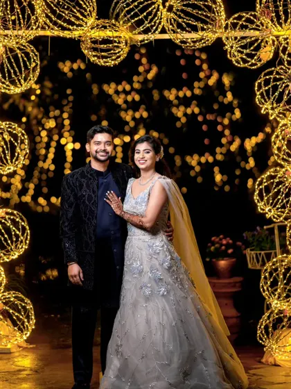 A classic portrait of the couple framed by the arch of glowing string-light orbs.