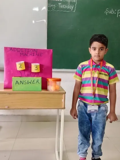 A student demonstrates his handmade 'Addition Machine'. This creative tool helps visualize the process of addition, making math intuitive and fun for our youngest learners.