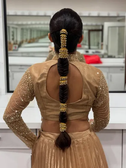 A sleek and modern take on a bubble braid, this style uses gold beaded accessories to create segments. It's a perfect look for a cocktail party or sangeet.