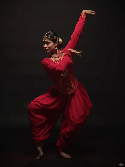 This image captures the fluidity and grace of the dancer's movement. The composition and lighting work together to create a timeless portrait of a traditional artist in her element.