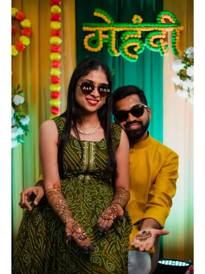 A fun and quirky photo of the couple wearing matching sunglasses, showing off their mehendi-adorned hands.