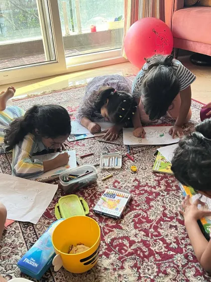 Deep in concentration. Our floor-based setup allows for comfortable, collaborative art-making, where kids can easily share ideas and materials.