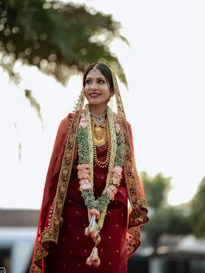 An outdoor portrait of a Coorgi bride in her red muhurtham saree. The natural light makes her skin glow.