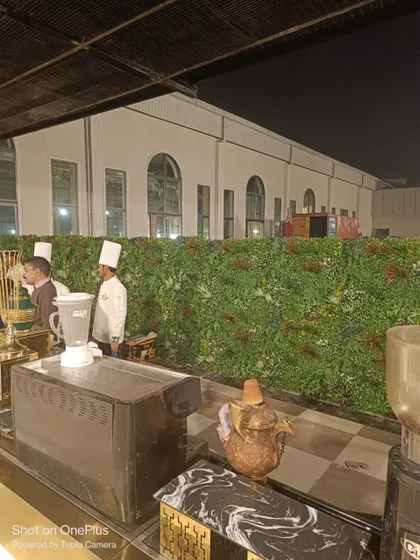 A temporary vertical green wall used as a backdrop for a catering station at an event. It's a simple and effective way to enhance the decor and define different zones.