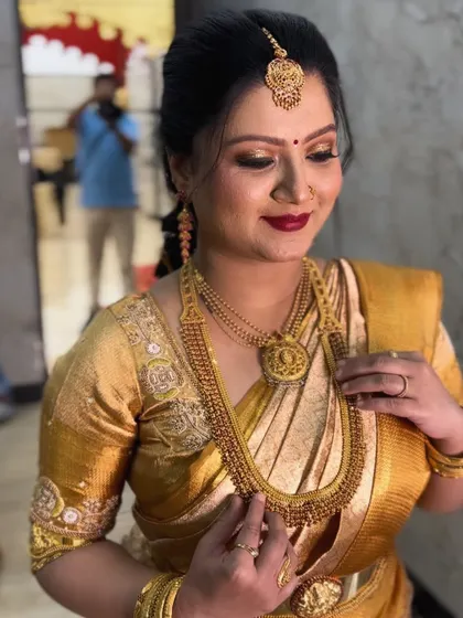 A beautiful, classic look for a naming ceremony. The client is wearing a gorgeous gold silk saree, and her makeup features a timeless red lip and defined eyes.
