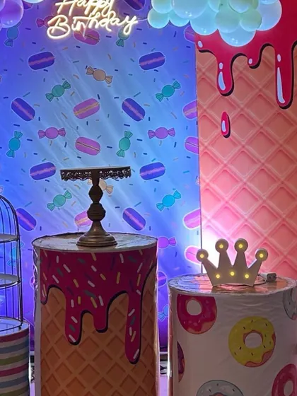 A fun dessert station at a candyland party, with themed pedestals, a light-up crown, and a colorful backdrop.