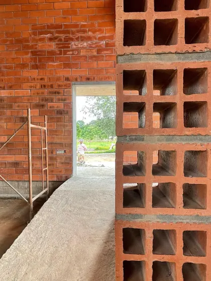 A detail of the perforated brick screen used in the 'Vault & Wall' house. This element allows for ventilation and light while maintaining privacy and creating beautiful shadow patterns.