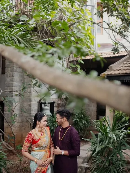 A couple framed by the foliage and the rustic stone buildings of the courtyard, a perfect blend of nature and architecture.